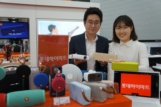 20일 롯데하이마트 서울 대치점에서 고객들이 미니 빔프로젝터, 블루투스 스피커 등을 선보이고 있다. <롯데하이마트 제공>